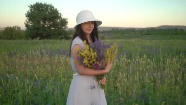 Ung kvinna som går med bukett av fält blommor. — Stockvideo