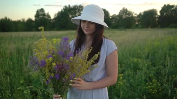 Ung kvinna som går med bukett av fält blommor. — Stockvideo