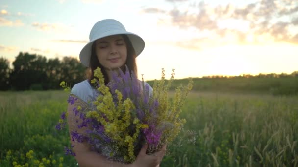 Mujer joven caminando con ramo de flores de campo . — Vídeo de stock