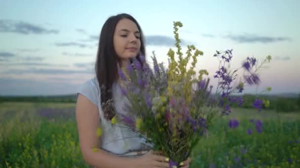 Νεαρή γυναίκα περπάτημα με μπουκέτο λουλούδια χωράφι. — Αρχείο Βίντεο