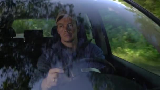 Genç adam yaz günü orman tarafında boyunca araba sürüş etrafında bakıyor. — Stok video