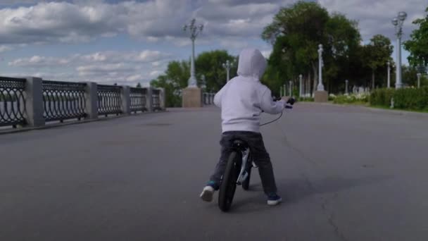 Sevimli 3-4 yıl çocuk çocuk öğrenme ilk koşu dengesi bisiklet binmek. — Stok video