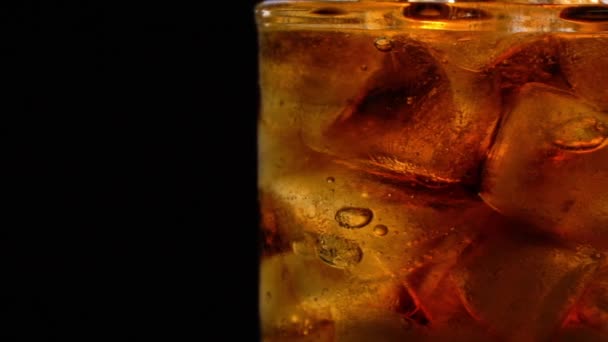 Cola con hielo y burbujas en vidrio giran sobre negro — Vídeos de Stock