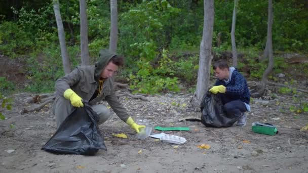 Voluntarios con bolsas de basura limpiando el bosque — Vídeo de stock