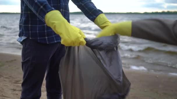 Voluntarios recogiendo basura en una playa solitaria — Vídeos de Stock