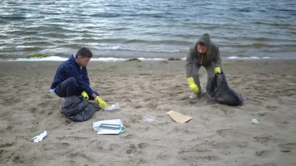 Vrijwilligers heffen vuilnis op in het strand — Stockvideo