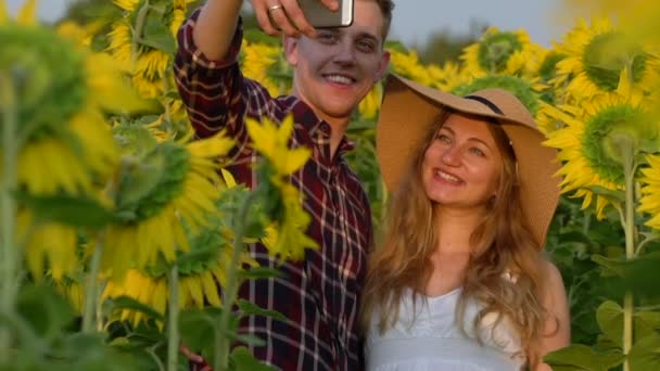 Mężczyzna i kobieta w ciąży zrobić selfie w słoneczniki pole — Wideo stockowe