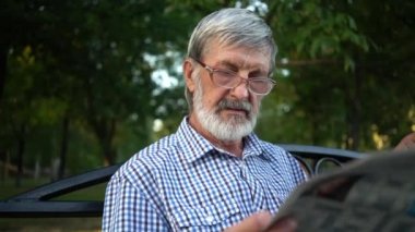 ekose gömlek üst düzey parkta bir bankta oturur ve bir gazete okur