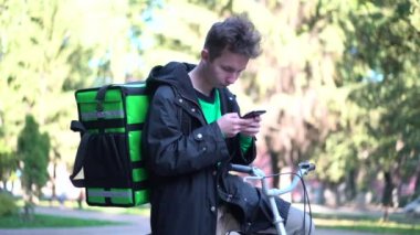 yeşil bagpack ve bisiklet ile teslimat adam telefonda müşteri adresi arıyor