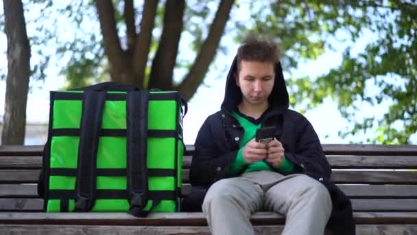 Курьер с зеленым багажом в ожидании заказа на доставку — стоковое видео