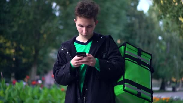 Delivery man with green backpack awaiting the order for delivery — Stock Video