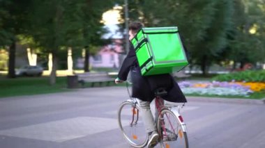 yeşil bagpack ile teslimat adam gıda teslimat ile şehir üzerinden bir bisiklet sürmek
