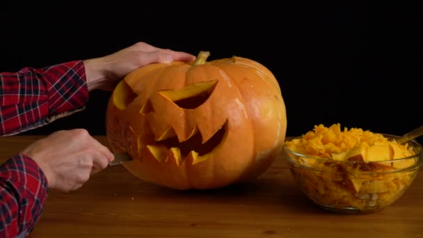Мужчины вырезают тыкву с фонариком на Хэллоуин — стоковое видео