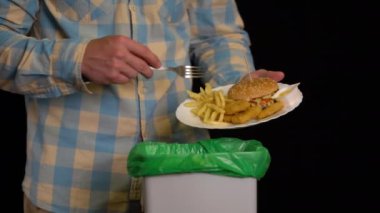 Bir tabak ile kazıma adam bir burger, patates kızartması, nuggets, çöp kutusuna peynir sosu