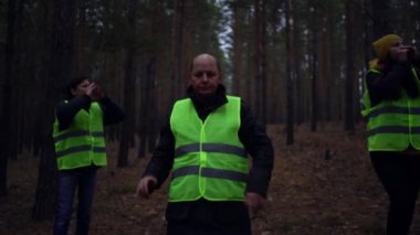 Yeşil yelekli bir grup gönüllü bir çam ormanında kayıp kişileri aramaya gitti.