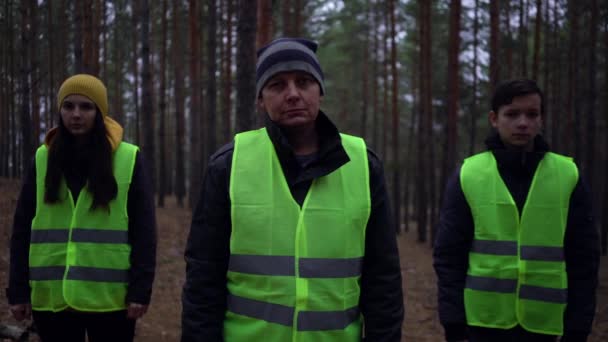 Zöld mellényes önkéntesek egy csoportja eltűnt személyek után kutatott egy fenyőerdőben. — Stock videók