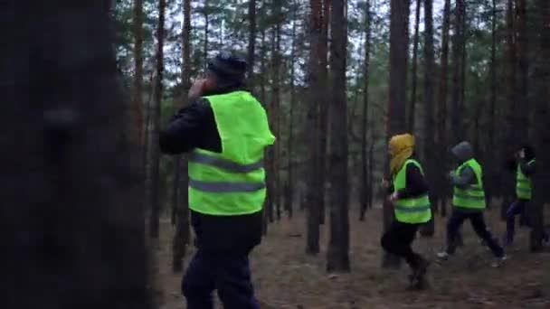 Grupo de voluntarios en chalecos verdes fueron en busca de personas desaparecidas en un bosque de pinos — Vídeos de Stock