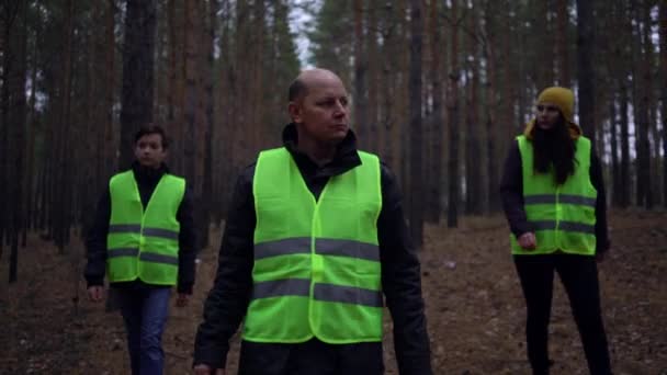 Група волонтерів у зелених жилетах вирушила на пошуки зниклих у сосновому лісі — стокове відео