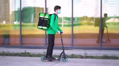 Tıbbi maske takan genç kurye siparişi mobiletle teslim ediyor..