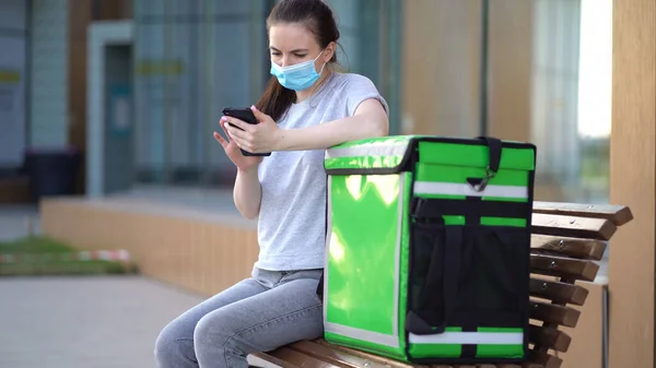 Mulher de entrega com bolsa verde aguardando a ordem de entrega — Fotografia de Stock