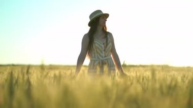 Bir tarlada kolları açık yürüyen bir kadın.