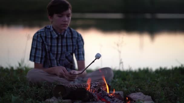 Jonge toerist roosterend marshmallow over het kampvuur bij de camping — Stockvideo