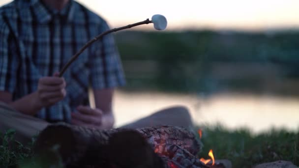 캠핑 근처의 모닥불 위에서 마시멜로를 볶는 젊은 관광객 — 비디오