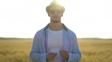 Şapkalı bir çiftçi buğday tarlasında yürüyor.