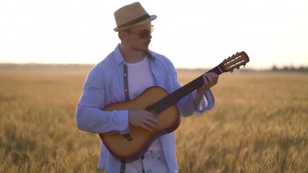 Gra na gitarze akustycznej na zewnątrz w polu pszenicy — Wideo stockowe