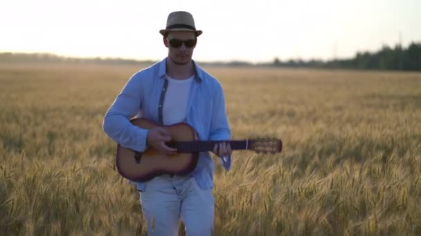 Tocando guitarra acústica ao ar livre em campos de trigo — Vídeo de Stock