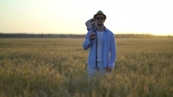 Junger Mann steht mit Gitarre im Weizenfeld. — Stockvideo
