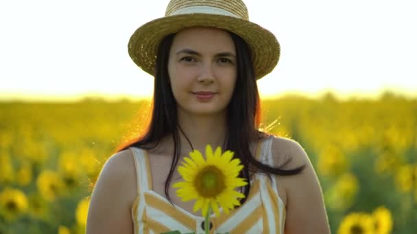 Красива молода жінка з капелюхом тримає в руках соняшник — стокове відео