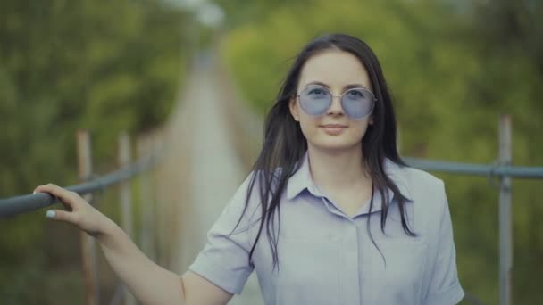 Mulher retrato em um vestido bonito, de pé em uma ponte na floresta — Vídeo de Stock