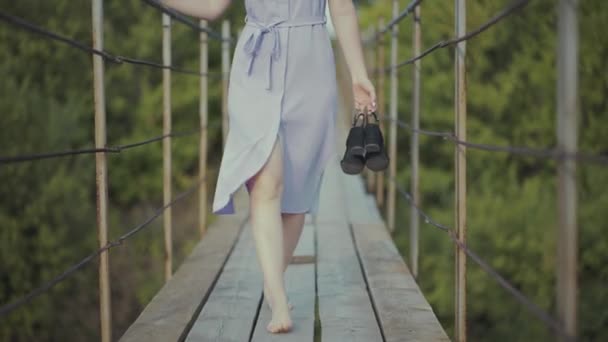 Kobieta w pięknej sukience, spaceruje po moście w lesie — Wideo stockowe