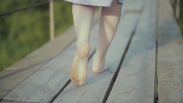 Mulher em um vestido bonito, caminha em uma ponte na floresta — Vídeo de Stock