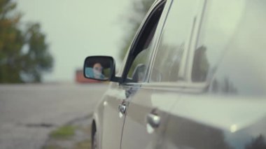 Şoför yol kenarındaki araba camından hamburger kutusunu atıyor..