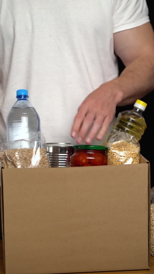 Egy önkéntes ételt tesz egy adománydobozba. Jótékonysági koncepció — Stock videók
