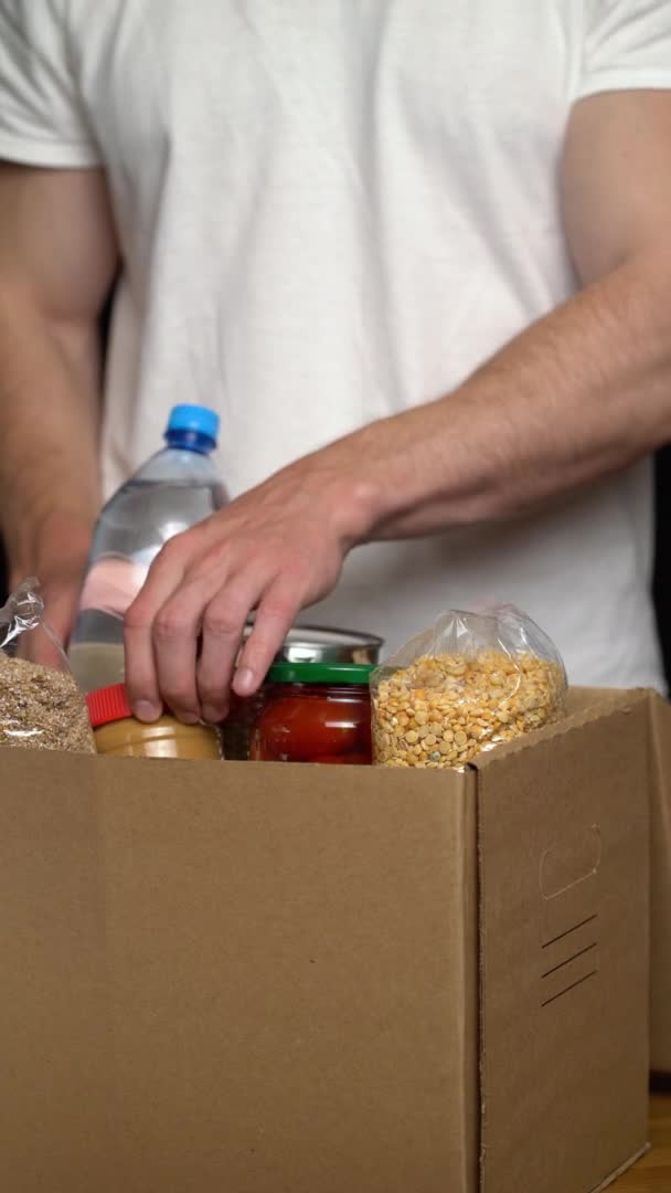 Frivillig att lägga mat i en donationslåda. Begreppet välgörenhet — Stockvideo