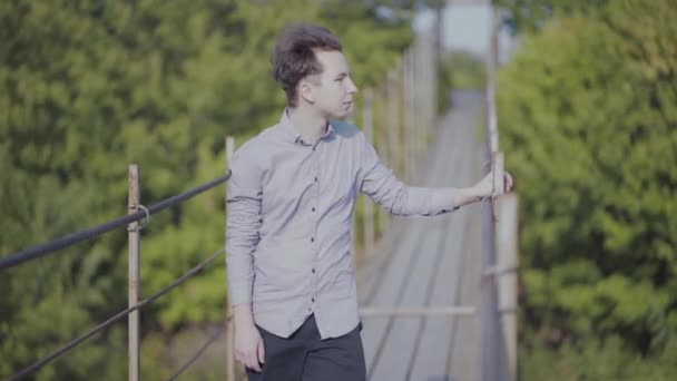 Guy walks on suspended bridge in the forest — Stock Video