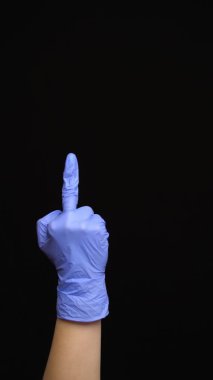 Lateks eldivenli kadın eli siyah arka planda izole edilmiş orta parmak hareketi yapar.