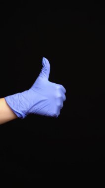 Lateks eldivenli kadın eli siyah arka planda izole edilmiş bir jest yapar..