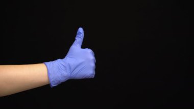 Lateks eldivenli kadın eli siyah arka planda izole edilmiş bir jest yapar.
