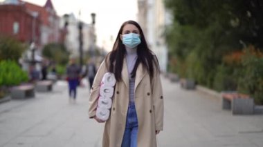 Kadınlar ikinci dalga karantina sırasında tuvalet kağıdıyla tıbbi maskeyle yürüyorlar. Coronavirus COVID-19 salgını.
