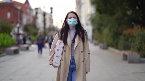 Frauen gehen in medizinischer Maske mit Toilettenpapier während der zweiten Quarantäne-Welle des Coronavirus COVID-19 Pandemie — Stockvideo