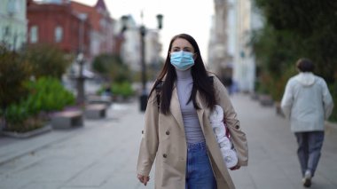 Kadınlar ikinci dalga karantina sırasında tuvalet kağıdıyla tıbbi maskeyle yürüyorlar. Coronavirus COVID-19 salgını.
