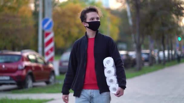 Teen walking in medical mask with toilet paper during the second wave quarantine coronavirus COVID-19 pandemic — Stock Video