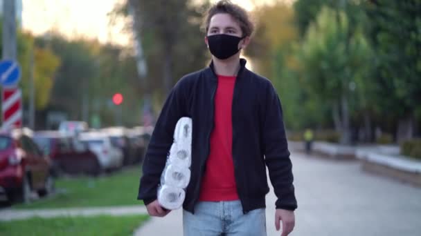 Nastolatek spacerujący w masce medycznej z papierem toaletowym podczas drugiej fali kwarantanny koronawirusa COVID-19 pandemia — Wideo stockowe