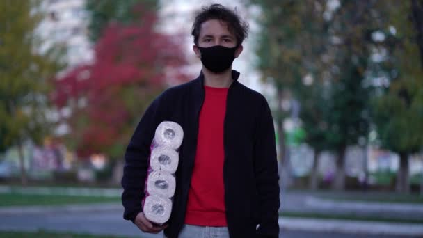 Teen walking in medical mask with toilet paper during the second wave quarantine coronavirus COVID-19 pandemic — Stock Video