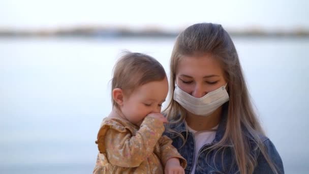 Maschera madre tiene per mano bella figlia sulla spiaggia a piedi durante la seconda ondata di quarantena coronavirus COVID-19 pandemia — Video Stock