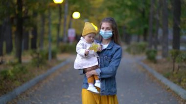 Maskeli anne, ikinci dalga karantina Coronavirus COVID-19 salgını sırasında sevgili kızının elini tutuyor.